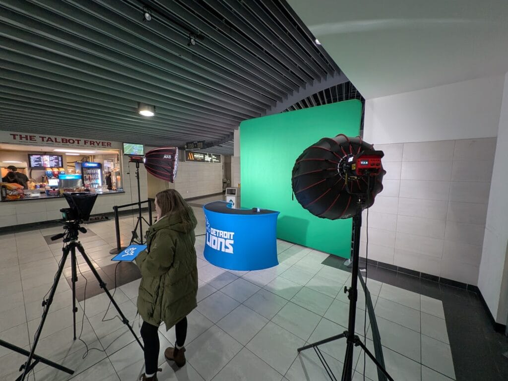 Detroit Lions Game Cast Booth with branded sports desk, professional microphones, and green screen setup